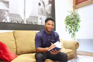 dam Tolliver sits on a couch at the Foundation for the Mid South, writing in a notebook and reflecting during his internship.