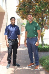 Adam Tolliver and George Stewart stand side by side outside, smiling in front of a tree on the Foundation’s office building.