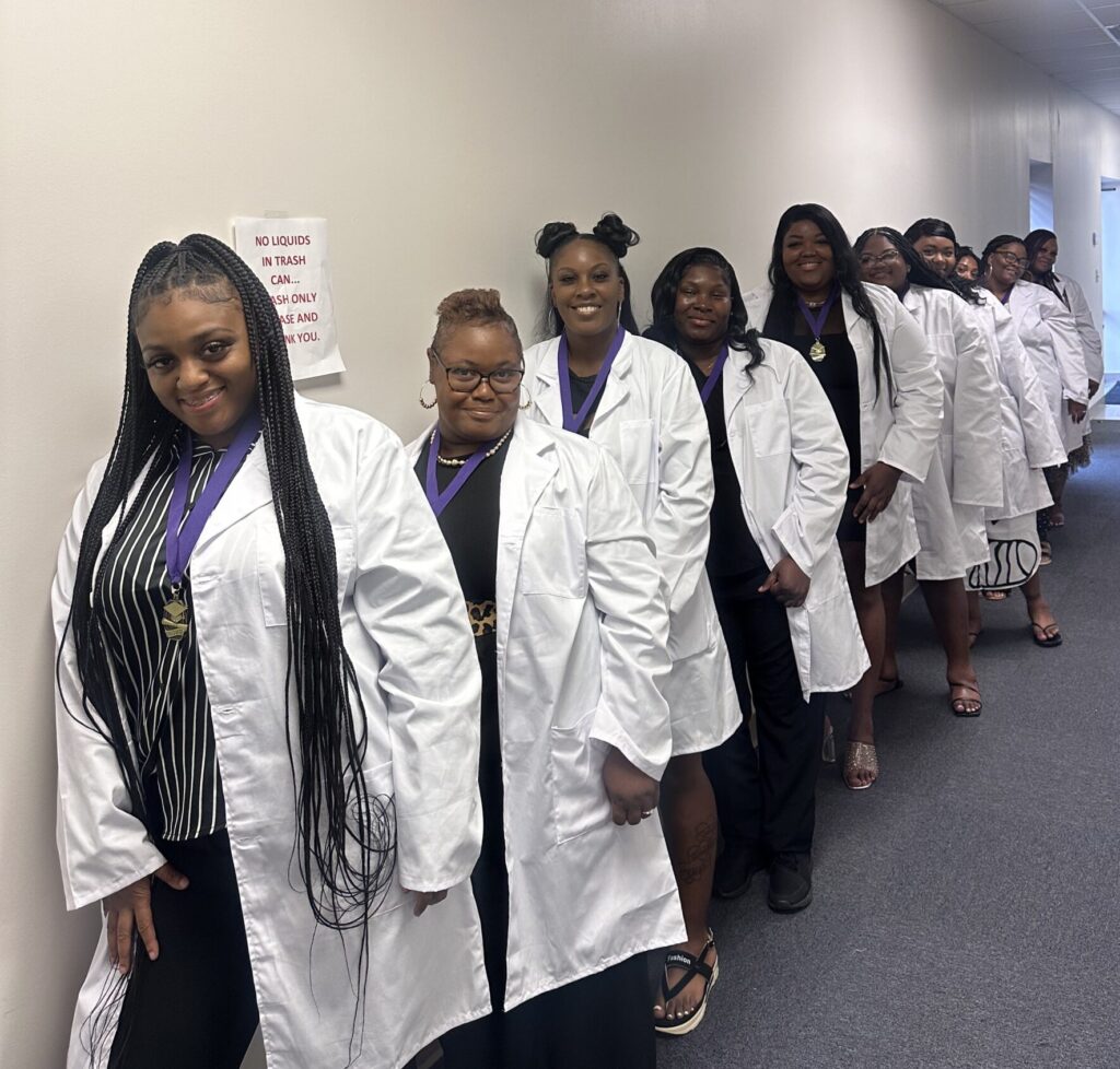 A group of students in white coats stand along a wall during training at 180 Career Center, symbolizing new opportunities for healthcare careers in the Delta.