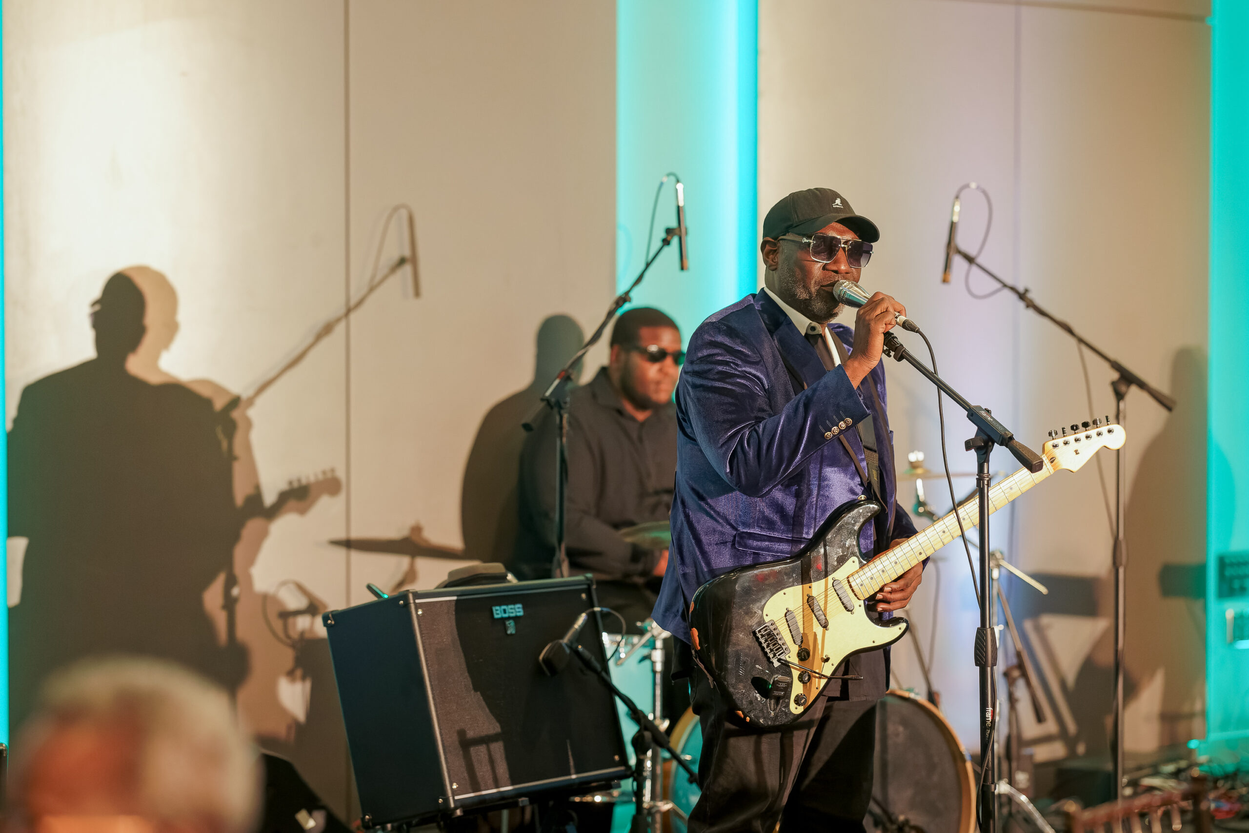 Stevie J sings and plays guitar onstage during the Foundation for the Mid South’s 35th Anniversary celebration, lit by teal lights.