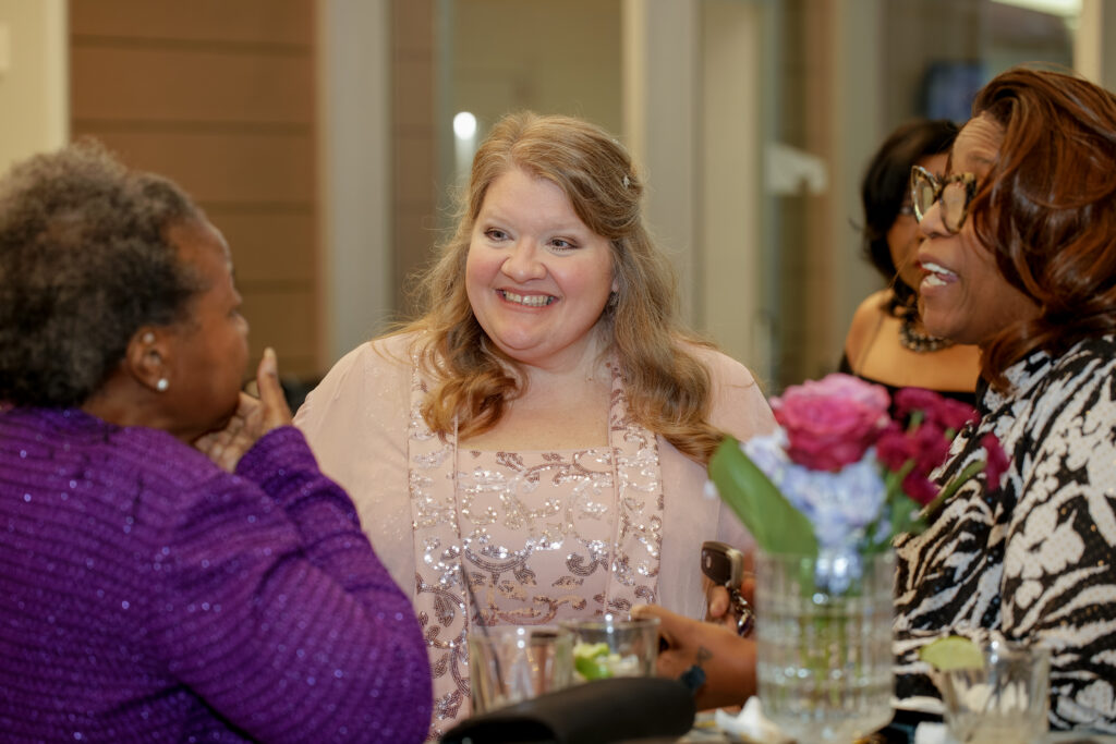 Former FMS staff member Martha Claire laughing and talking with two guests during the anniversary celebration.