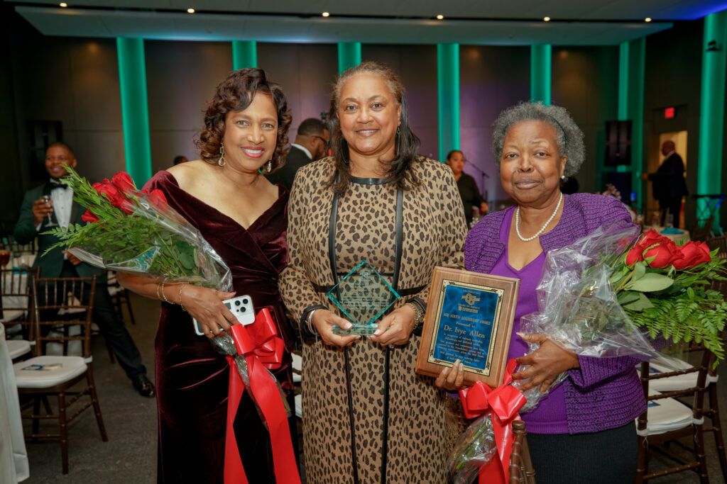 Meshelle Rawls, Rhea Bishop, and Dr. Ivye Allen pose together holding flowers and awards after the ceremony.