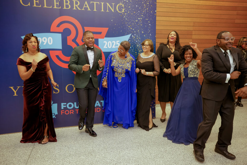 Foundation for the Mid South staff members dancing together in front of the anniversary backdrop.