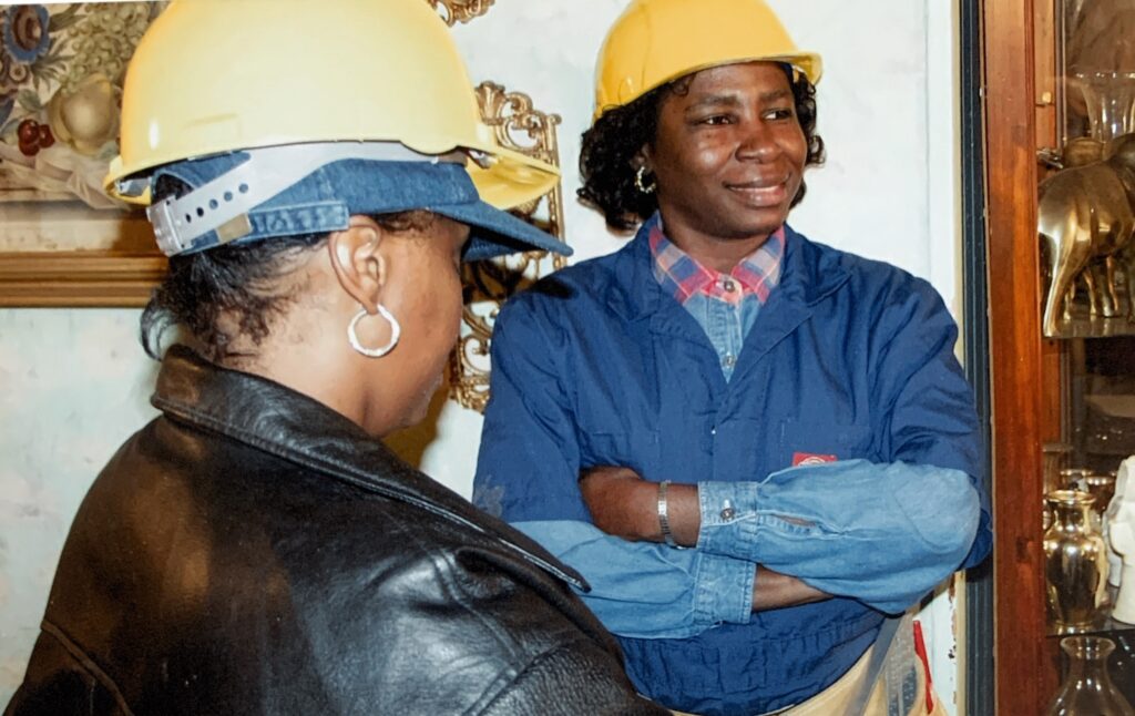 Two women wearing hard hats in a workplace setting during a workforce initiative.